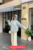 Person wearing a blue and white checkered raincoat standing outside a store with an open sign.