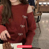 Person wearing a red sweater with bow details in an indoor setting
