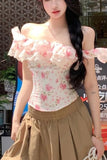 Woman wearing a floral off-shoulder top and beige pants in an outdoor setting.