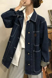 Person wearing a dark blue denim jacket over a white shirt.