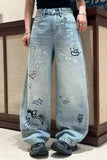 Light blue jeans with black designs worn by a person, standing against a wooden panel background.