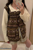 Person wearing a patterned vest over a white sweater and skirt, taking a mirror selfie.