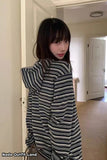 Person wearing a black and white striped dress in a room with beige carpet and white walls.