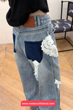 Denim jeans with lace detailing worn by a person, on a wooden floor.
