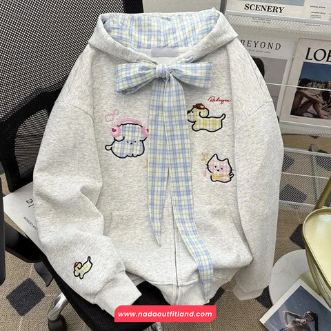 Gray hoodie with cartoon designs and a plaid bow on a chair.
