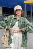 Person wearing a green plaid shirt, white pants, and beige cap outdoors.