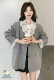 Woman in a gray blazer with lace details holding a coffee cup against a plain background
