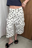 Person wearing white pants with black polka dots and a navy top with white polka dots.
