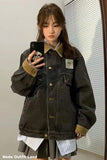 Person wearing a dark denim jacket with a brand logo, taking a mirror selfie.