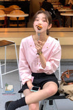 Woman in a pink shirt eating a piece of food in a casual setting