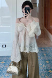 Person wearing a white lace top and brown pants, taking a mirror selfie.