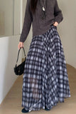 Person wearing a plaid skirt and gray sweater indoors.