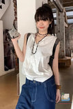 Person wearing a white sleeveless top and blue pants indoors.