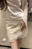 Person wearing a white lace skirt with a plain background