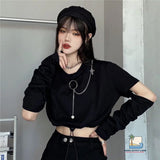 Person wearing a black outfit with a headband and jewelry, standing against a plain background.