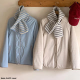 Two jackets with scarves and a red cap hanging on a wooden rack.