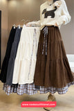Woman wearing a white sweater with a dog design, holding a brown tiered skirt, with other skirts displayed on hangers.