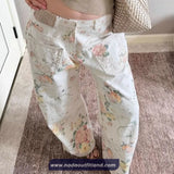 Floral-patterned jeans being worn on a carpeted floor with a neutral background.