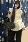 Person wearing a white sweater and black pants standing in front of blue lockers.