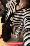 Person wearing a black and white striped sweater with floral details, holding a black handbag.