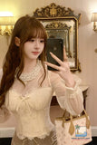 Woman taking a mirror selfie wearing a lace top and holding a phone.
