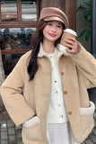 Woman in a beige coat and hat holding a coffee cup outdoors.