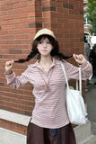 Woman with braided hair wearing a striped shirt and cap against a brick wall.