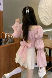 Person wearing a pink top with a bow and white skirt in a casual setting.