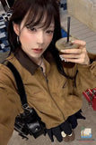 Person holding a drink with a straw, wearing a brown jacket and black gloves.