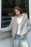 Woman wearing a light gray jacket with fur trim standing against a building exterior.