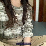 Person wearing a striped shirt and beige pants sitting on the floor.