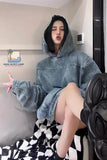 Person wearing a denim hoodie sitting on a couch with a visible brand logo in the corner.