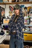 Person wearing a plaid shirt and cap in a workshop setting