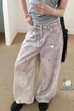 Person wearing light-colored jeans with decorative elements in a room.
