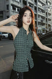 Woman in a green plaid dress standing next to a car in an urban setting
