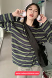 Person wearing a striped shirt with a black bag, indoors.