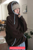 Person wearing a brown hoodie with a hood in a room.