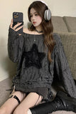 Woman sitting on a couch wearing a gray sweater with a star design, holding a phone.