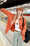 Person wearing an orange plaid jacket and white shirt with a tiger design, standing in a subway station.