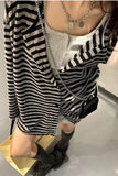 Person wearing a black and white striped outfit with layered necklaces on a plain background