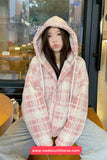 Person wearing a pink plaid hoodie sitting inside a building.