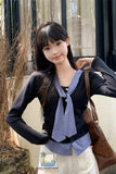 Woman wearing a black sweater with a blue checkered scarf, standing outdoors.