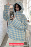 Person wearing a blue and white checkered jacket taking a mirror selfie.