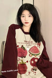 Person wearing a maroon and beige long-sleeve shirt with cartoon designs and text.