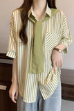 Person wearing a layered outfit with a striped shirt and green top.