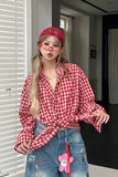 Person wearing a red and white checkered shirt with a pink cap and glasses indoors.