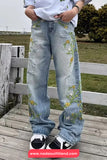 Person wearing light blue jeans with floral embroidery standing on a wooden deck.