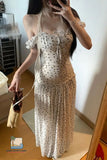 Woman wearing a polka dot dress holding a small bag indoors.