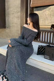 Woman in a long gray off-shoulder dress sitting on a bench.