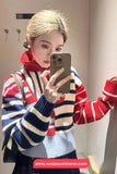Person wearing a colorful striped sweater taking a mirror selfie.